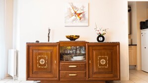 A wooden cabinet with glass doors, a bowl on top, and a vase with flowers on the right. - L'Intemporel - Appartement T3 avec jardinet - 3* (Poitiers)