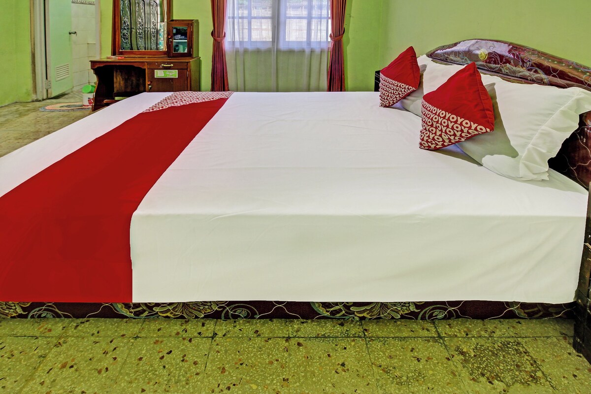 A bed with a red and white bedspread, a wooden headboard, and red and white pillows.