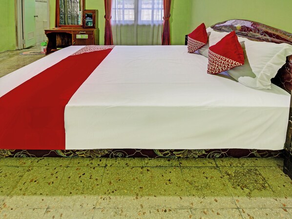 A bed with a red and white bedspread, a wooden headboard, and red and white pillows.