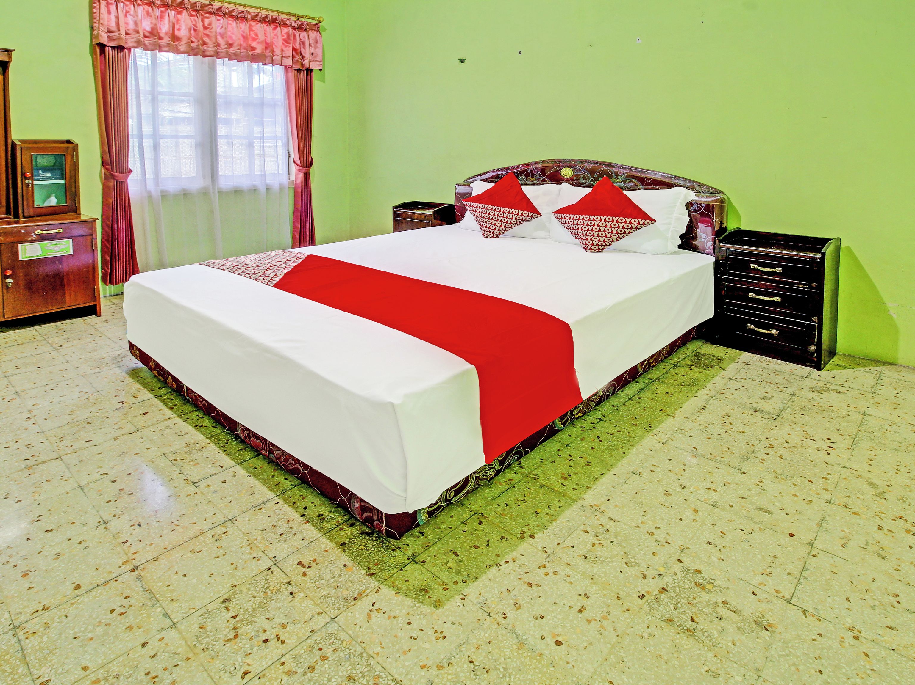 Una habitación de hotel con una cama grande, un aparador de madera y una mesita de noche.