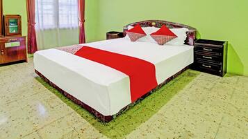Una habitación de hotel con una cama grande, un aparador de madera y una mesita de noche.