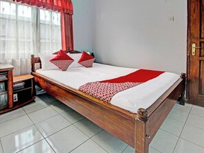 A wooden bed with a white mattress and red accents, a nightstand with books, and a window with curtains. - Spot ON 91214 Desa Wisata Pandean (Dongko)