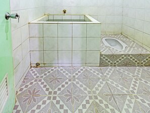 A bathroom with a bathtub, a toilet, and patterned floor tiles.
