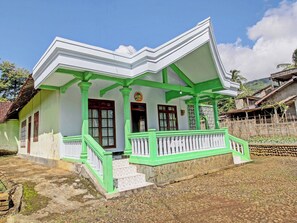 A traditional house with a green and white color scheme, featuring a porch with a staircase leading to the entrance. - Spot ON 91214 Desa Wisata Pandean (Dongko)