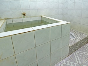 A bathroom with a bathtub, tiled walls, and a patterned floor. - Spot ON 91214 Desa Wisata Pandean (Dongko)
