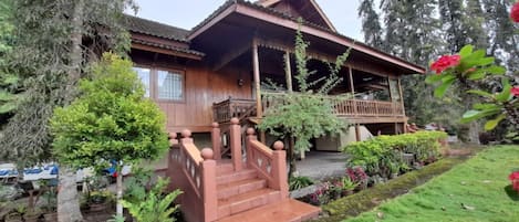 A wooden house with a porch and steps leading to a covered area.