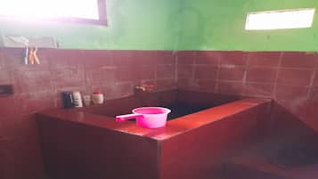 Un baño con un lavabo rojo y un lavamanos rosa, y una ventana.