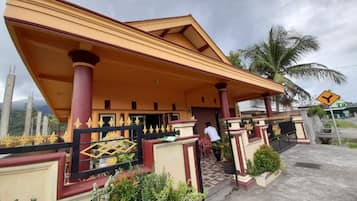 A building with a covered entrance, a gated area with decorative fencing, and a palm tree in the background.