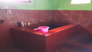 Une salle de bain avec un lavabo rouge, un receveur de douche rose et une fenêtre.