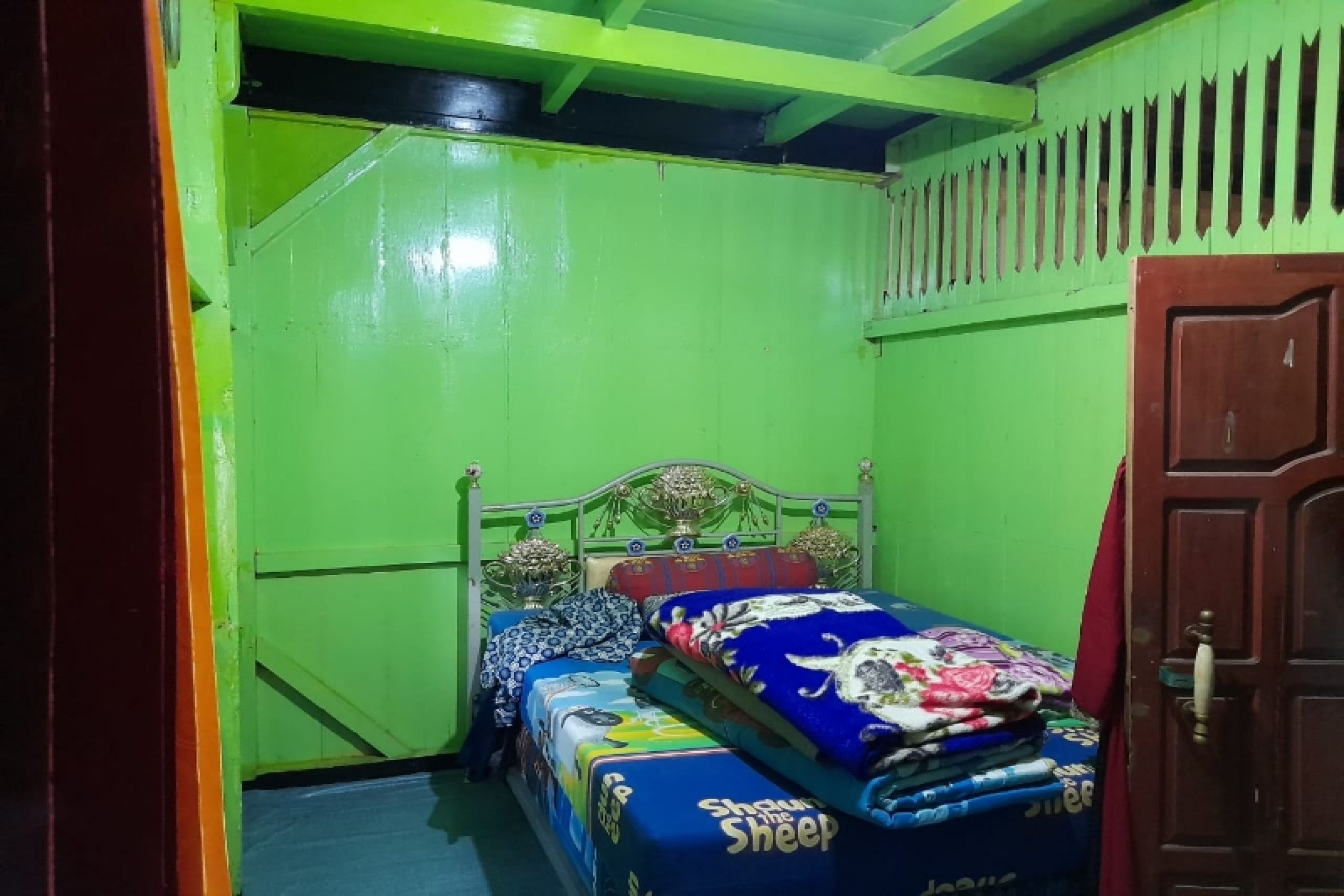 A room with a bed, a door, and a green wall.