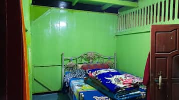 Una habitación con una cama, una puerta y una pared verde.