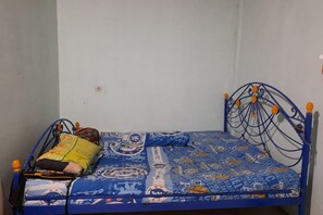 Una habitación pequeña con una cama individual, estructura de metal y edredón estampado.