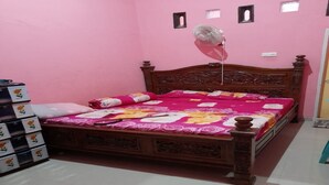 Une chambre à coucher avec un lit en bois, des murs roses et un ventilateur de plafond.