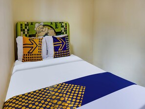 A bed with a white and blue bedspread, two pillows with yellow and blue patterns, and a green headboard with a cartoon character. - OYO Homes 91132 Desa Wisata Kalipucang (Purwosari)