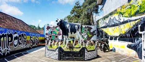 Un estacionamiento con un gran mural de una vaca y un edificio con techo de tejas.
