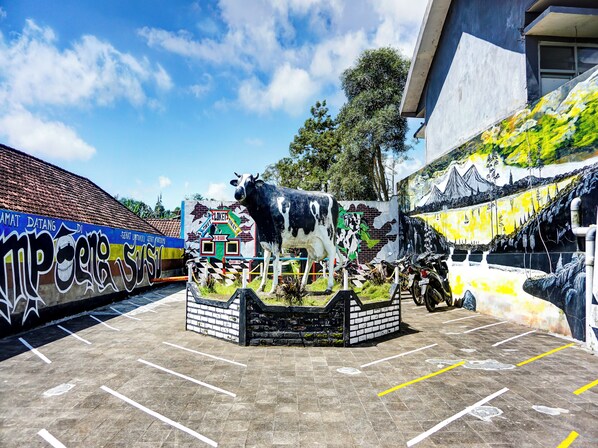 Un espace de stationnement orné d’une grande fresque représentant une vache et un bâtiment doté d’un toit recouvert de tuiles.