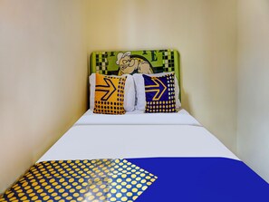 A bed with a white mattress and a blue and yellow patterned blanket. There are two pillows with yellow and blue designs. - OYO Homes 91132 Desa Wisata Kalipucang (Purwosari)