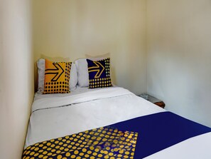 Un lit avec une literie blanche et deux oreillers aux motifs jaunes et bleus.