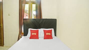 A hotel room with a bed, a headboard, curtains, and a window.