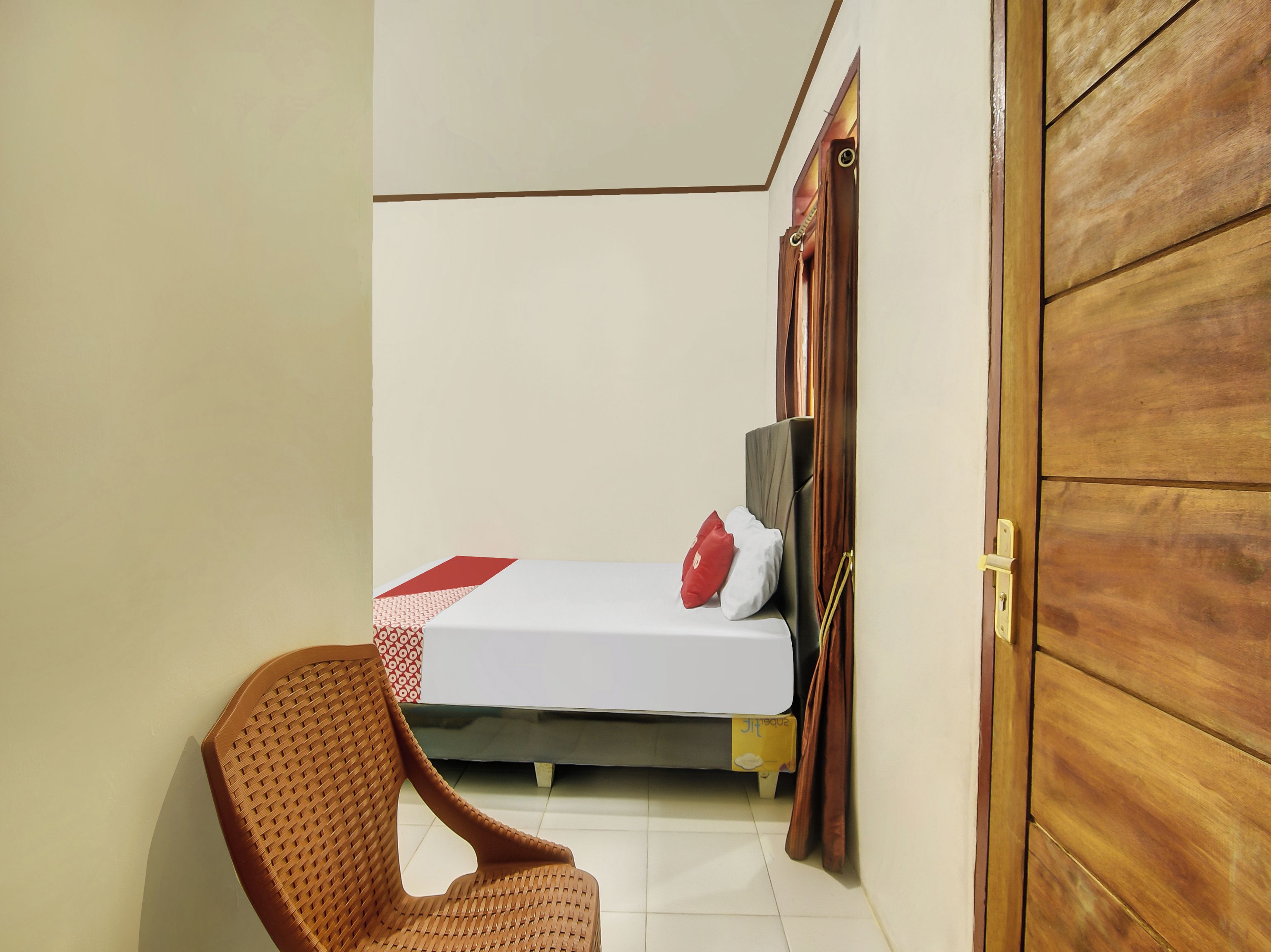 A room with a bed, a chair, and a wooden door.