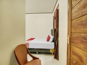 Ein Zimmer mit einem Bett, einem Stuhl und einer Holztür.