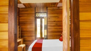 Ein holzgetäfeltes Zimmer im Blockhausstil mit einem Bett, einer kleinen Bank und einem Fenster mit Gitterwerk.