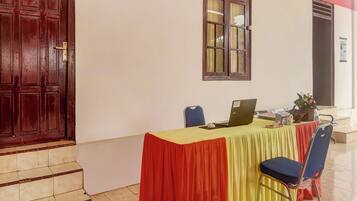 Una habitación con escritorio, silla, una computadora portátil y ventana con cortinas.