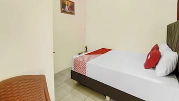 Un dormitorio con cama, mesita de noche, un cuadro en la pared y una silla.