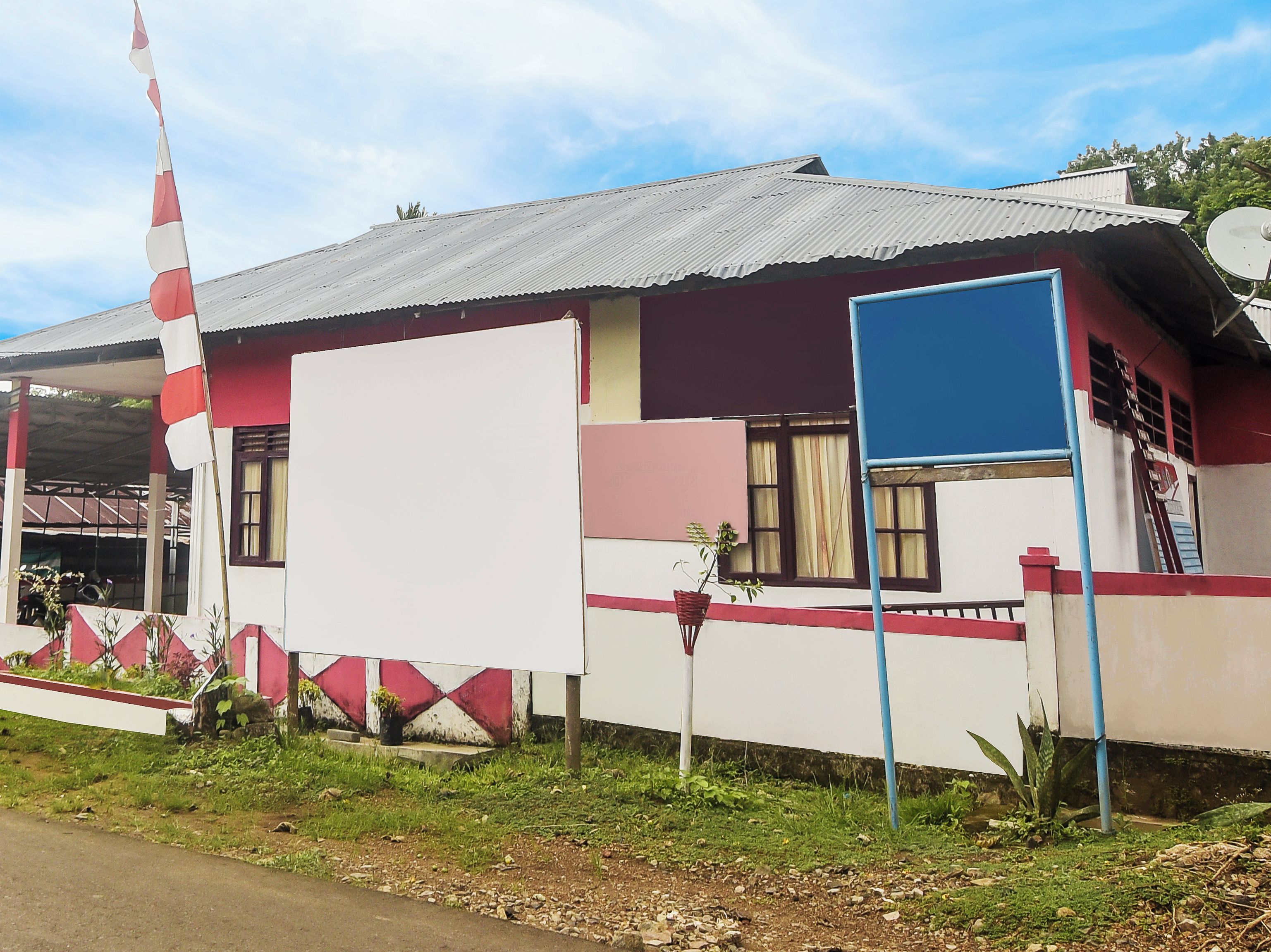 A building with a corrugated metal roof, a large white wall, and a red and white striped flag.
