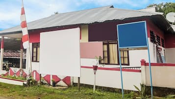 A building with a corrugated metal roof, a large white wall, and a red and white striped flag.