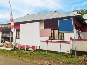 Un bâtiment doté d’un toit en tôle ondulée, d’un grand mur blanc et d’un drapeau rayé de rouge et de blanc.