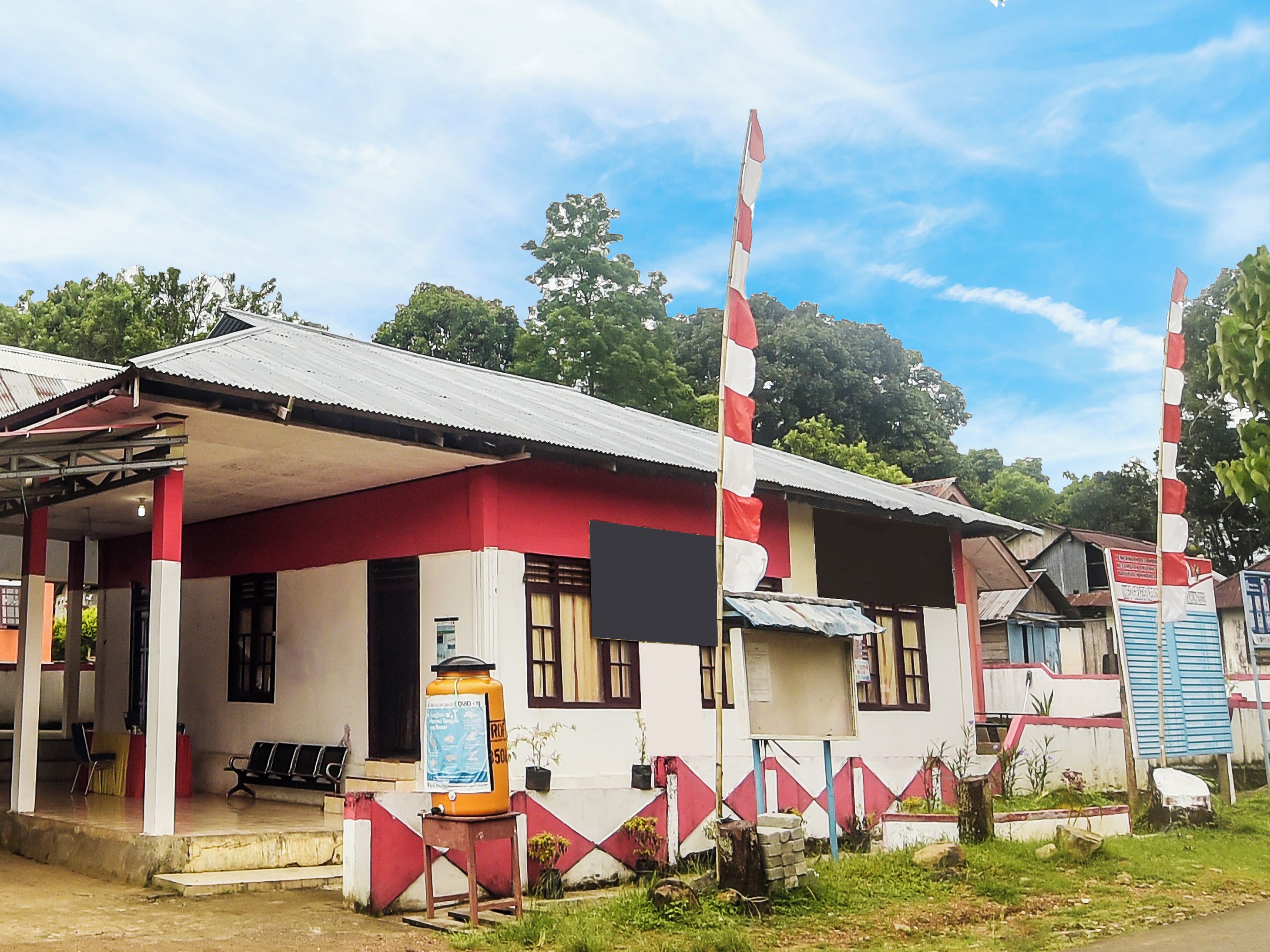A building with a red and white facade, a covered porch, and a flagpole.