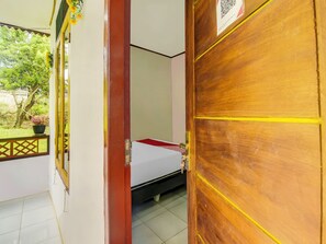 Ein Zimmer mit einem Bett, einem Fenster mit Blick ins Grüne und einer Tür mit einem QR-Code.