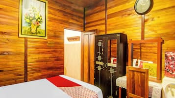 Una camera in legno con un letto, un armadio, una sveglia e un quadro appeso al muro.