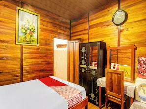Een houten kamer met een bed, een kledingkast, een klok en een schilderij aan de muur.