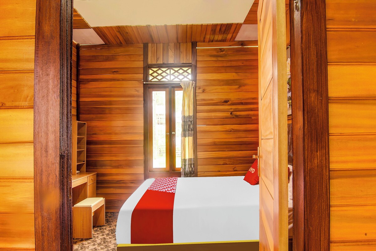 Ein holzgetäfeltes Zimmer im Blockhausstil mit einem Bett, einer kleinen Bank und einem Fenster mit Gitterwerk.