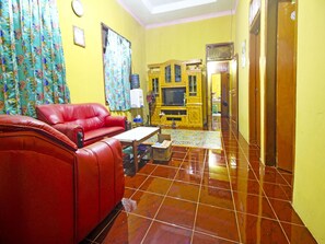 A living room with a red sofa, a television, and a water dispenser.