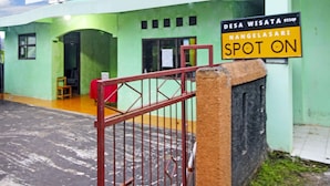 A building with a green facade, a sign reading 'DESA WISATA NANGELASARI SPOT ON,' and a red gate. - OYO Homes 91149 Desa Wisata Nangelasari (Nangelasari)
