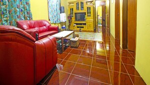A living room with a red sofa, a television, and a water dispenser. - OYO Homes 91149 Desa Wisata Nangelasari (Nangelasari)
