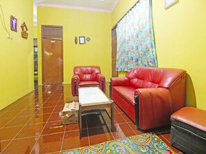 A room with a red leather sofa, a matching armchair, a small table, and a patterned rug.