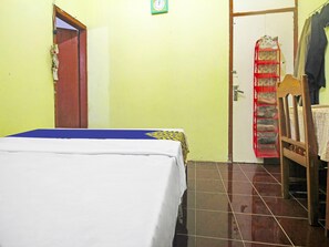 A room with a bed, a door, a wall clock, and a shoe rack. - OYO Homes 91149 Desa Wisata Nangelasari (Nangelasari)