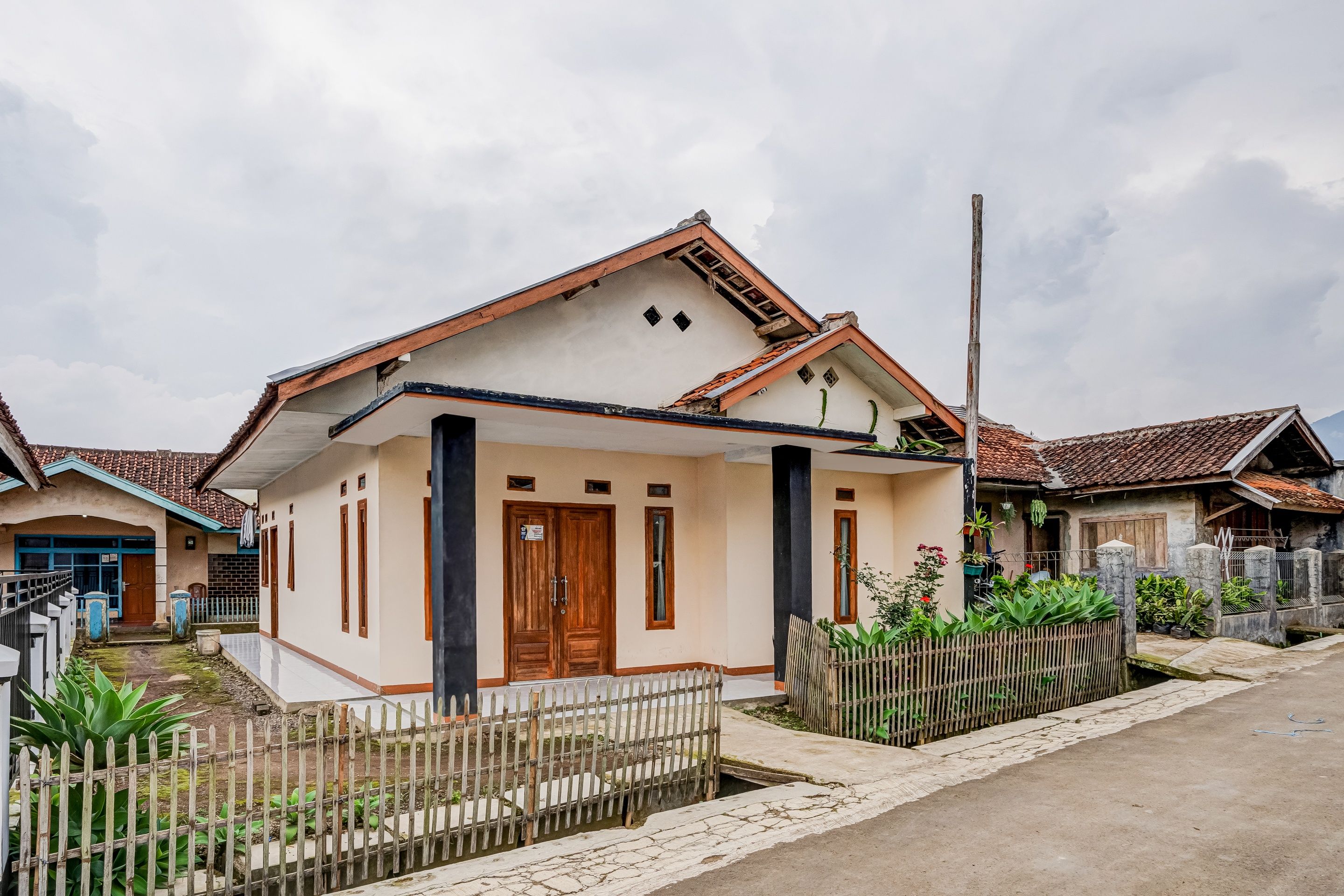 A single-story house with a tiled roof, a front porch, and a fenced yard.