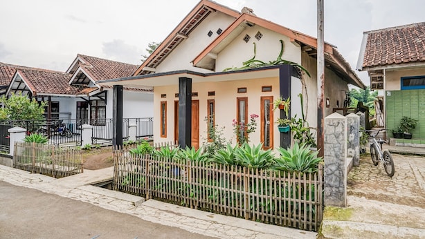 A residential house with a tiled roof, a wooden fence, and a paved driveway. - OYO 90997 Eco Desacibodasbabakangentong2syariah (Lembang)