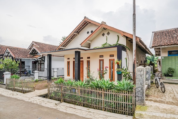 Une maison d’habitation avec un toit en tuiles, une clôture en bois et une allée pavée.