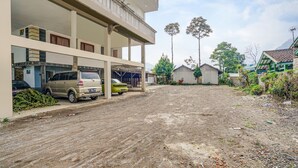 A multi-story building with a parking area, a dirt road, and greenery. - OYO 90997 Eco Desacibodasbabakangentong2syariah (Lembang)
