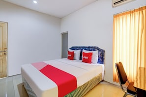 A hotel room with a bed, a chair, a door, and a window with curtains. - OYO 90935 Rumah Kost Metroliving (Surabaya)