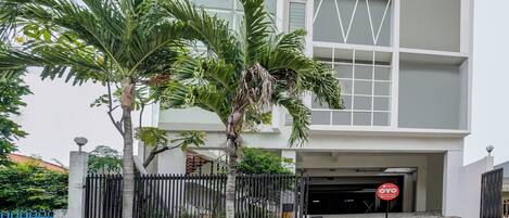 Un edificio moderno con entrada protegida por un portón, un cartel que indica zona residencial y un cielo despejado.