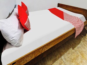 A single bed with white bedding and red accents, a wooden headboard, and a tiled floor. - OYO Homes 91134 Desa Wisata Tebing Lingga (Nglebo)