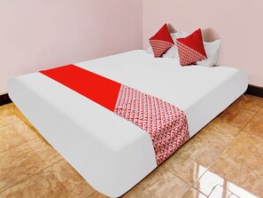 A bed with a white and red bedspread, two red pillows, and a pink wall. - OYO Homes 91134 Desa Wisata Tebing Lingga (Nglebo)