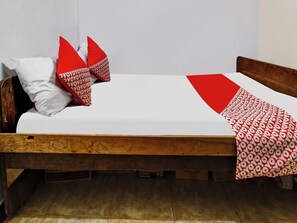 A single bed with a wooden frame, white bedding, and red and white patterned pillows. - OYO Homes 91134 Desa Wisata Tebing Lingga (Nglebo)